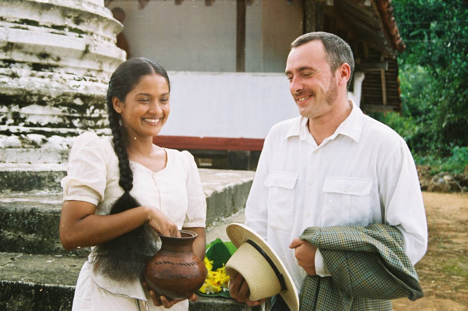 A village woman carrying a clay pot beside a British visitor at a temple