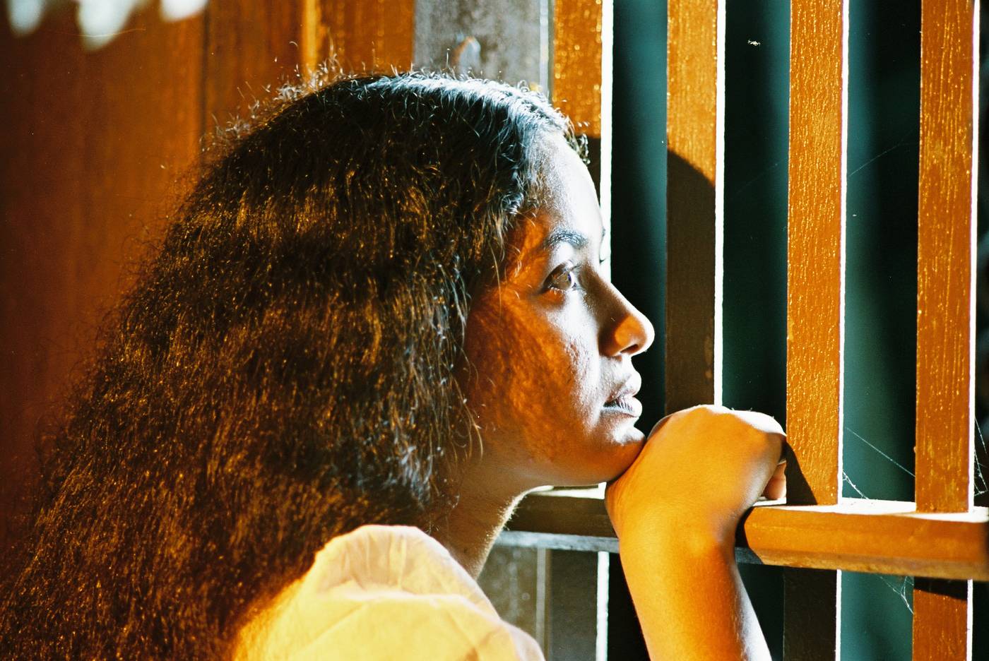 A woman looking out through window bars into evening light